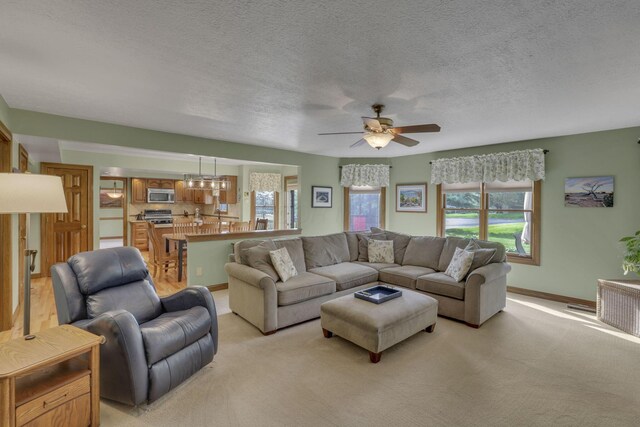 7689 Godfrey Cir, Reynoldsburg, OH 43068 - living room featuring ceiling fan, light colored carpet, a textured ceiling, and a chandelier
