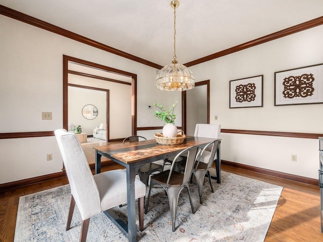 dining room with baseboards, a notable chandelier, light wood-style flooring, and ornamental molding