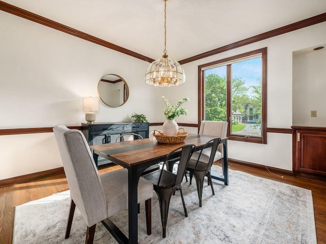 dining area featuring crown molding, light wood-type flooring, and a chandelier