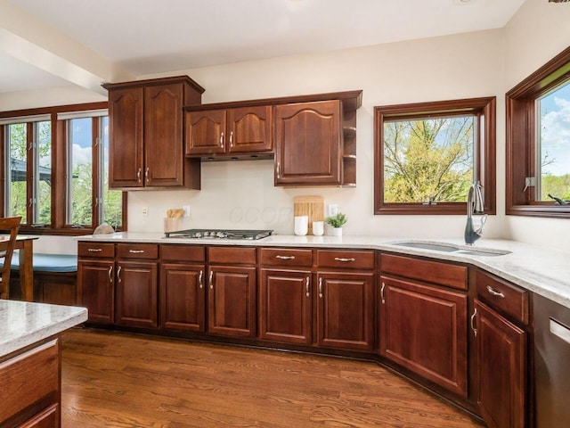 kitchen with appliances with stainless steel finishes, light stone counters, dark wood-style floors, and a sink