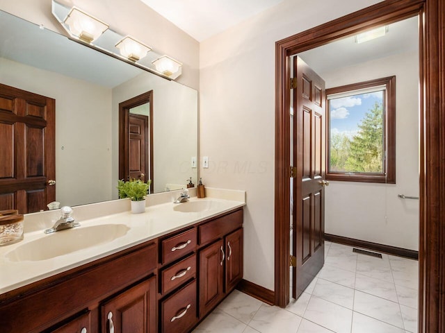 bathroom with baseboards, visible vents, a sink, and double vanity