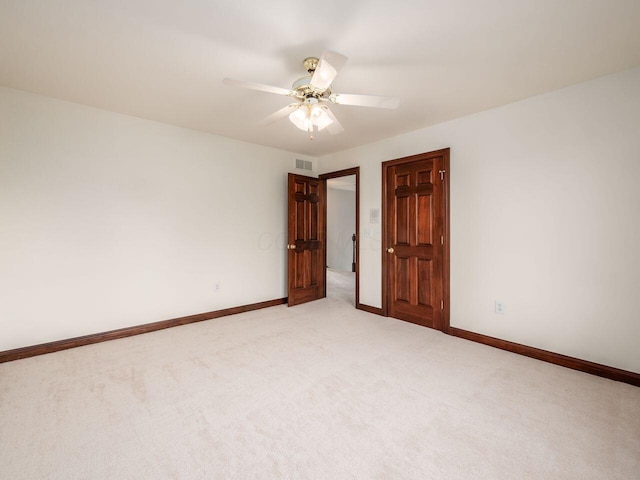 spare room featuring light carpet, baseboards, a ceiling fan, and visible vents