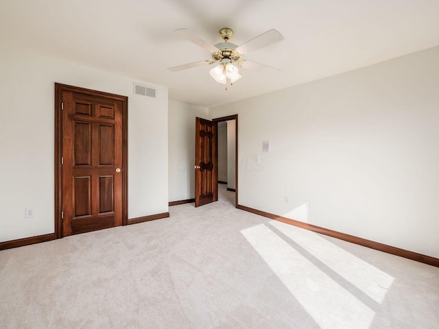 empty room featuring light carpet, baseboards, a ceiling fan, and visible vents