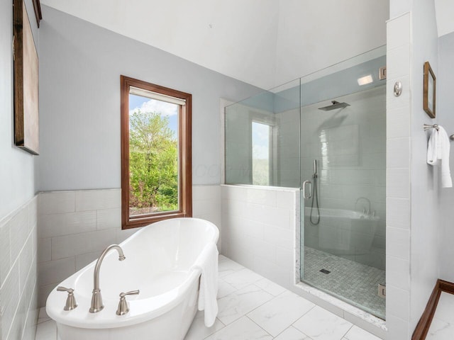 full bathroom featuring a wainscoted wall, a soaking tub, tile walls, a shower stall, and marble finish floor