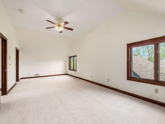 unfurnished room featuring light carpet, lofted ceiling, and a healthy amount of sunlight