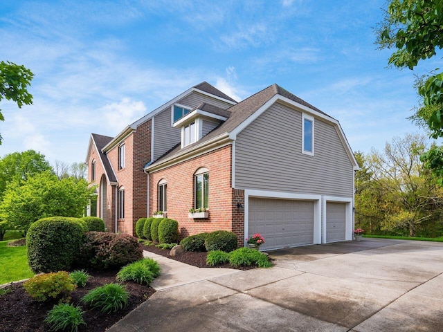 view of side of property featuring concrete driveway, a shingled roof, brick siding, and a garage