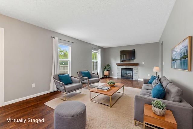living area with a textured ceiling, a glass covered fireplace, and wood finished floors