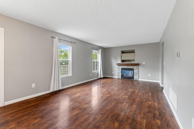 unfurnished living room with a textured ceiling, a glass covered fireplace, and wood finished floors