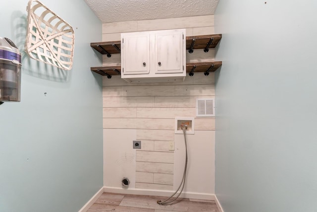 laundry area with electric dryer hookup, cabinet space, hookup for a washing machine, and light wood-style flooring