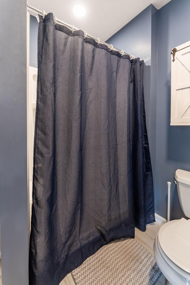 full bath with toilet, a shower with shower curtain, and wood finished floors