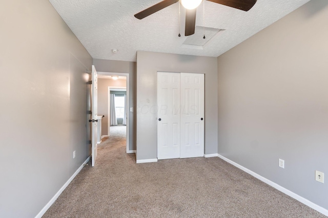 unfurnished bedroom featuring carpet flooring, a closet, a textured ceiling, and baseboards