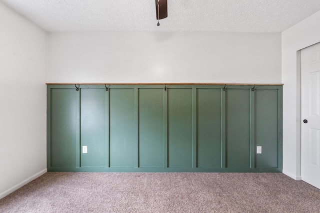 carpeted empty room with a textured ceiling, baseboards, and a ceiling fan
