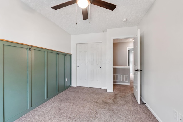 unfurnished bedroom featuring a textured ceiling, visible vents, ceiling fan, and carpet floors