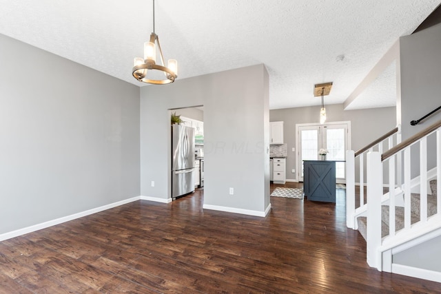 interior space featuring stairs, a textured ceiling, an inviting chandelier, dark wood-style floors, and baseboards