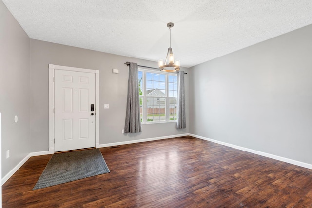 entryway with baseboards, an inviting chandelier, a textured ceiling, and wood finished floors