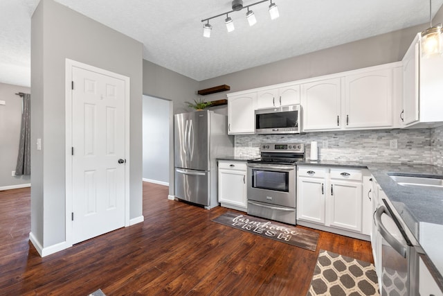 kitchen with stainless steel appliances, white cabinets, dark wood-style flooring, baseboards, and decorative backsplash