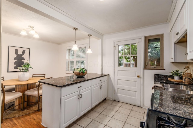 1775 NW Ct Unit 109, Columbus, OH 43212 - kitchen featuring a sink, ornamental molding, white cabinetry, a peninsula, and decorative light fixtures