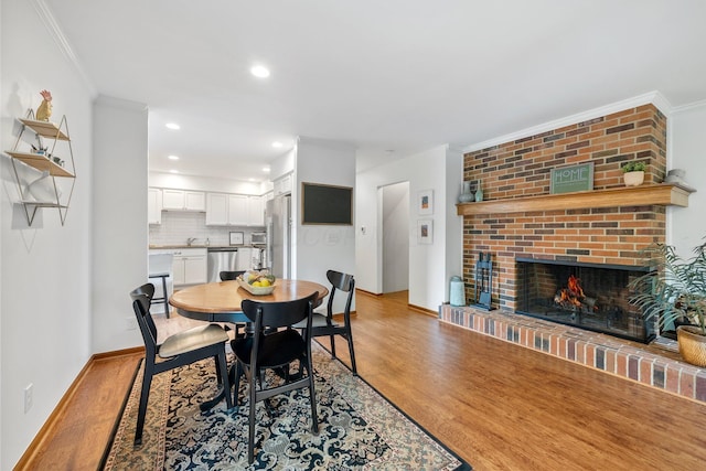 4216 Chaucer Ln, Columbus, OH 43220 - dining area with recessed lighting, baseboards, a brick fireplace, crown molding, and light wood-style floors