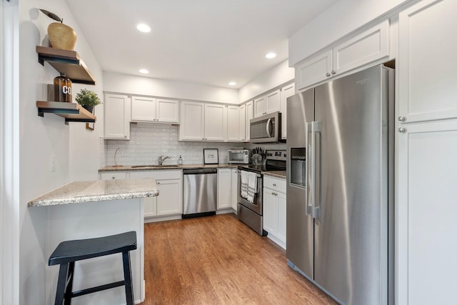 4216 Chaucer Ln, Columbus, OH 43220 - kitchen with open shelves, light wood-style floors, appliances with stainless steel finishes, decorative backsplash, and light stone counters
