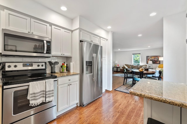 4216 Chaucer Ln, Columbus, OH 43220 - kitchen with light stone countertops, light wood-style flooring, recessed lighting, backsplash, and stainless steel appliances