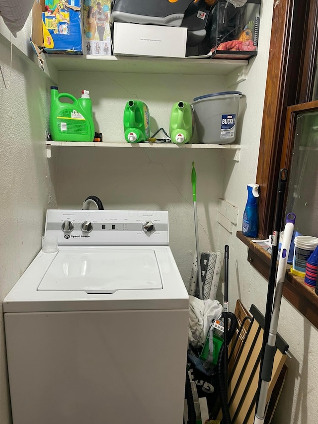 clothes washing area with washer / dryer, laundry area, and a textured wall