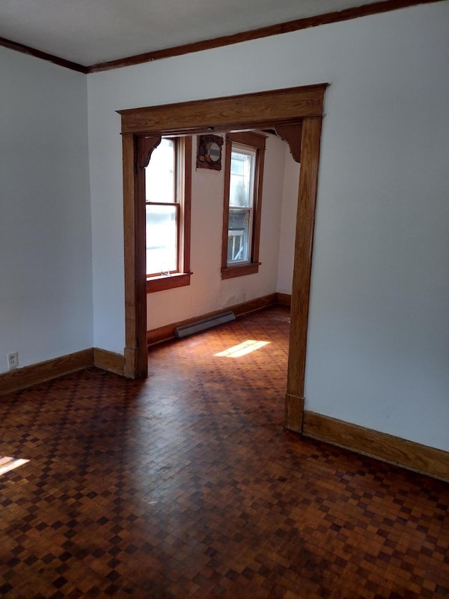 empty room with a baseboard radiator, ornamental molding, and baseboards