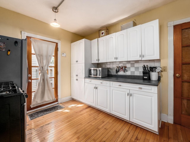 kitchen featuring white cabinets, dark countertops, appliances with stainless steel finishes, and tasteful backsplash