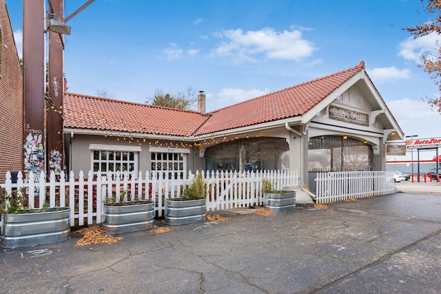 view of front of property featuring fence, a tiled roof, and a chimney