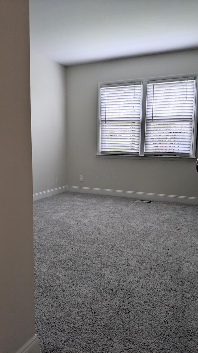 carpeted spare room featuring baseboards