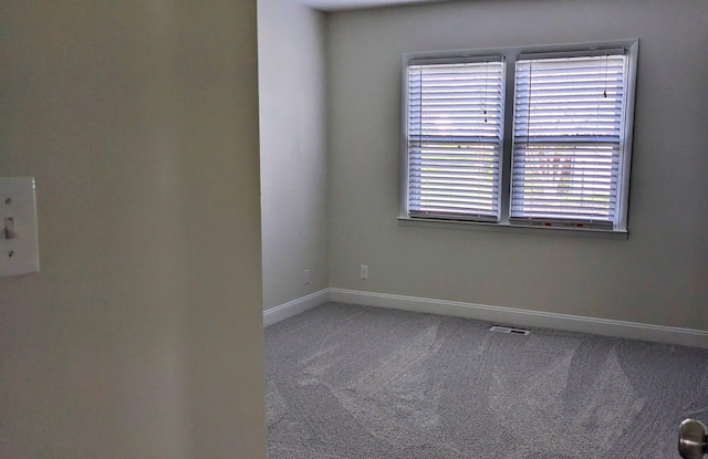 carpeted spare room featuring baseboards