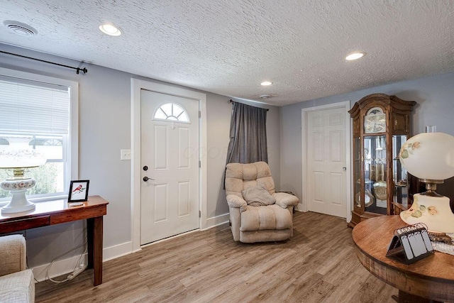 foyer entrance with a wealth of natural light, light wood-type flooring, visible vents, and a textured ceiling