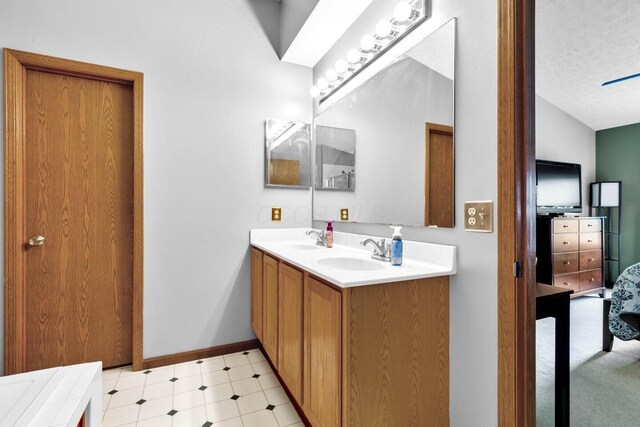 full bath featuring double vanity, a textured ceiling, baseboards, and a sink
