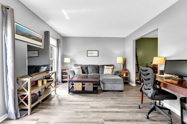 living area with baseboards, a textured ceiling, and wood finished floors