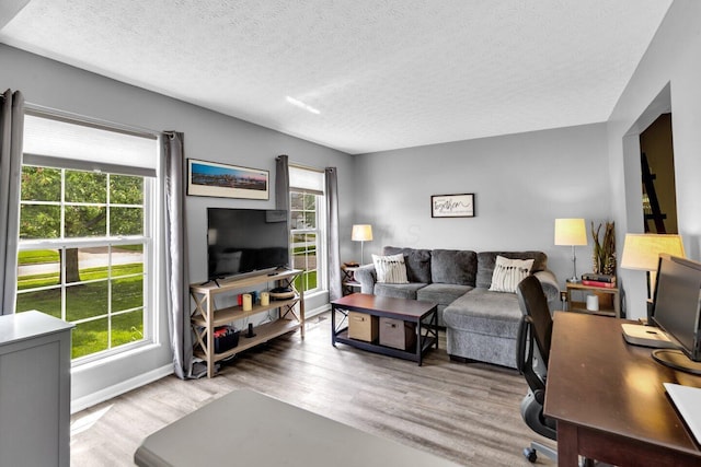 living room featuring a textured ceiling, wood finished floors, and baseboards