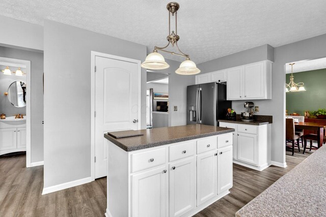 kitchen featuring dark countertops, stainless steel fridge with ice dispenser, dark wood-style floors, and white cabinets