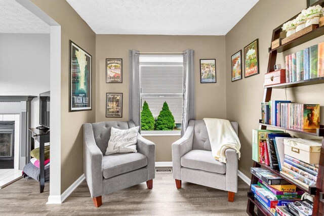 living area featuring a textured ceiling, visible vents, wood finished floors, and baseboards