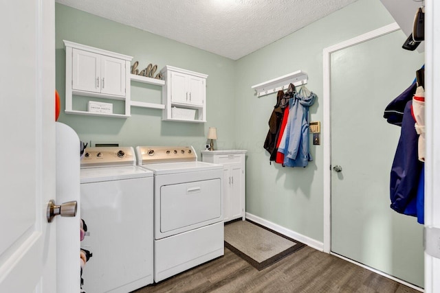clothes washing area with cabinet space, wood finished floors, a textured ceiling, separate washer and dryer, and baseboards