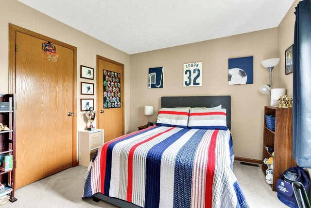bedroom featuring carpet flooring, visible vents, and a textured ceiling