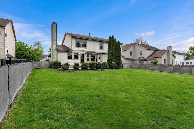 back of house featuring a yard, a chimney, and a fenced backyard