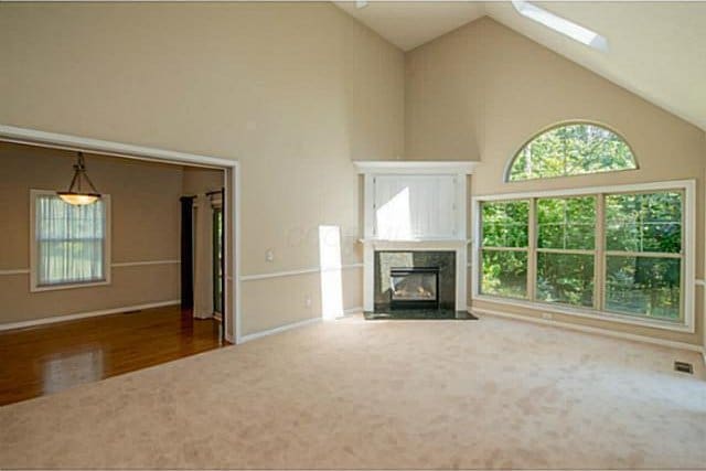 1139 Cross Creeks Rdg, Pickerington, OH 43147 - unfurnished living room with high vaulted ceiling, a high end fireplace, a skylight, carpet, and wood finished floors