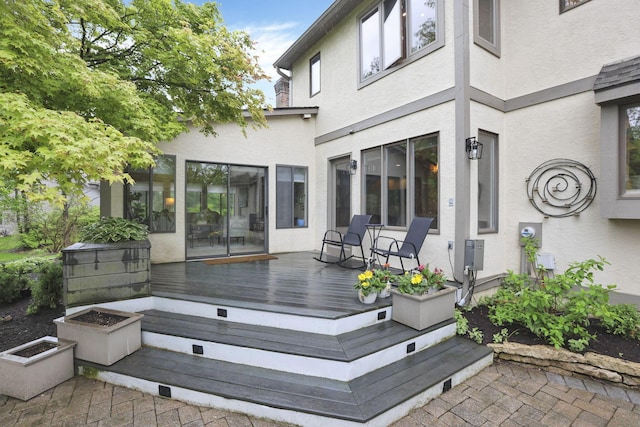 back of house with stucco siding and a deck