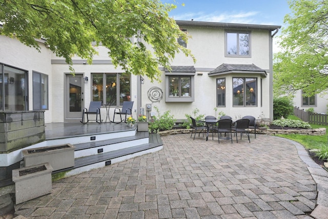 rear view of property featuring stucco siding, a patio area, and fence