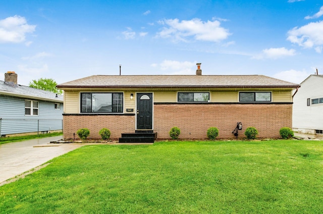 view of front of property with entry steps, brick siding, and a front lawn
