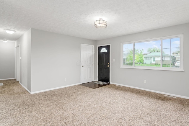 carpeted entryway with baseboards and a textured ceiling