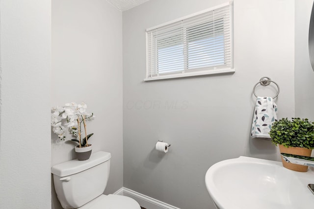 bathroom with a sink, toilet, and baseboards
