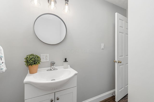 bathroom featuring baseboards, wood finished floors, and vanity
