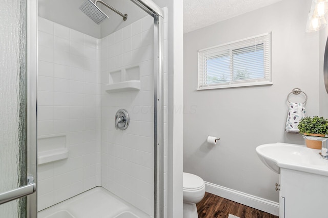 bathroom with toilet, wood finished floors, baseboards, a shower stall, and vanity
