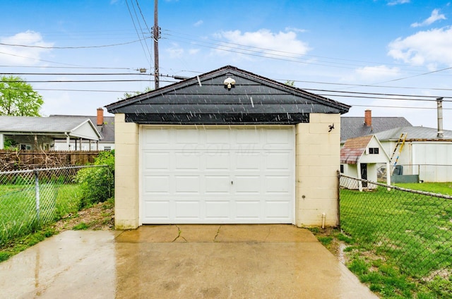 detached garage with concrete driveway and fence