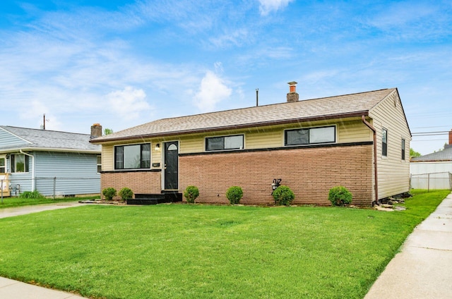 ranch-style home with brick siding, a chimney, fence, and a front yard