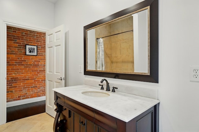 931 Dennison Ave, Columbus, OH 43201 - bathroom featuring wood finished floors, baseboards, vanity, and brick wall